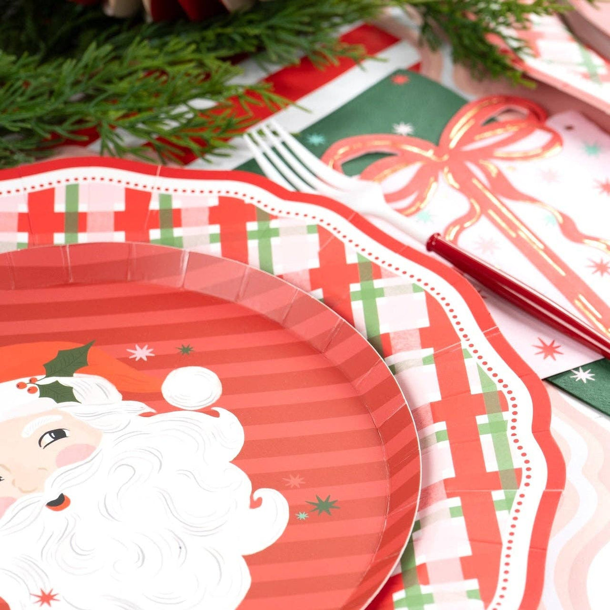 Angled view of a vintage Santa plate on the plaid dinner plate with a red bow and gold fork.