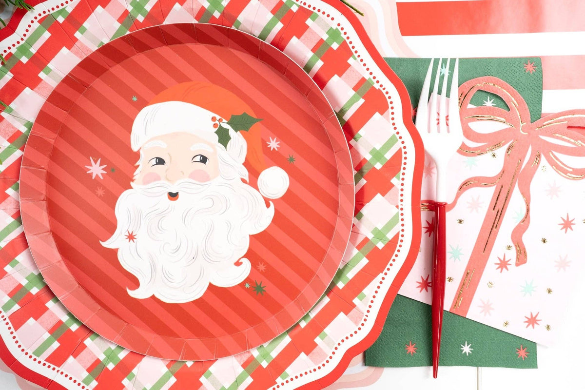 Place setting with a vintage Santa plate on the plaid dinner plate, a striped runner, and a red fork.