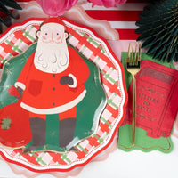 Place setting with a Santa plate on the plaid dinner plate, a green fringe tree, and a red "letters to Santa" napkin.