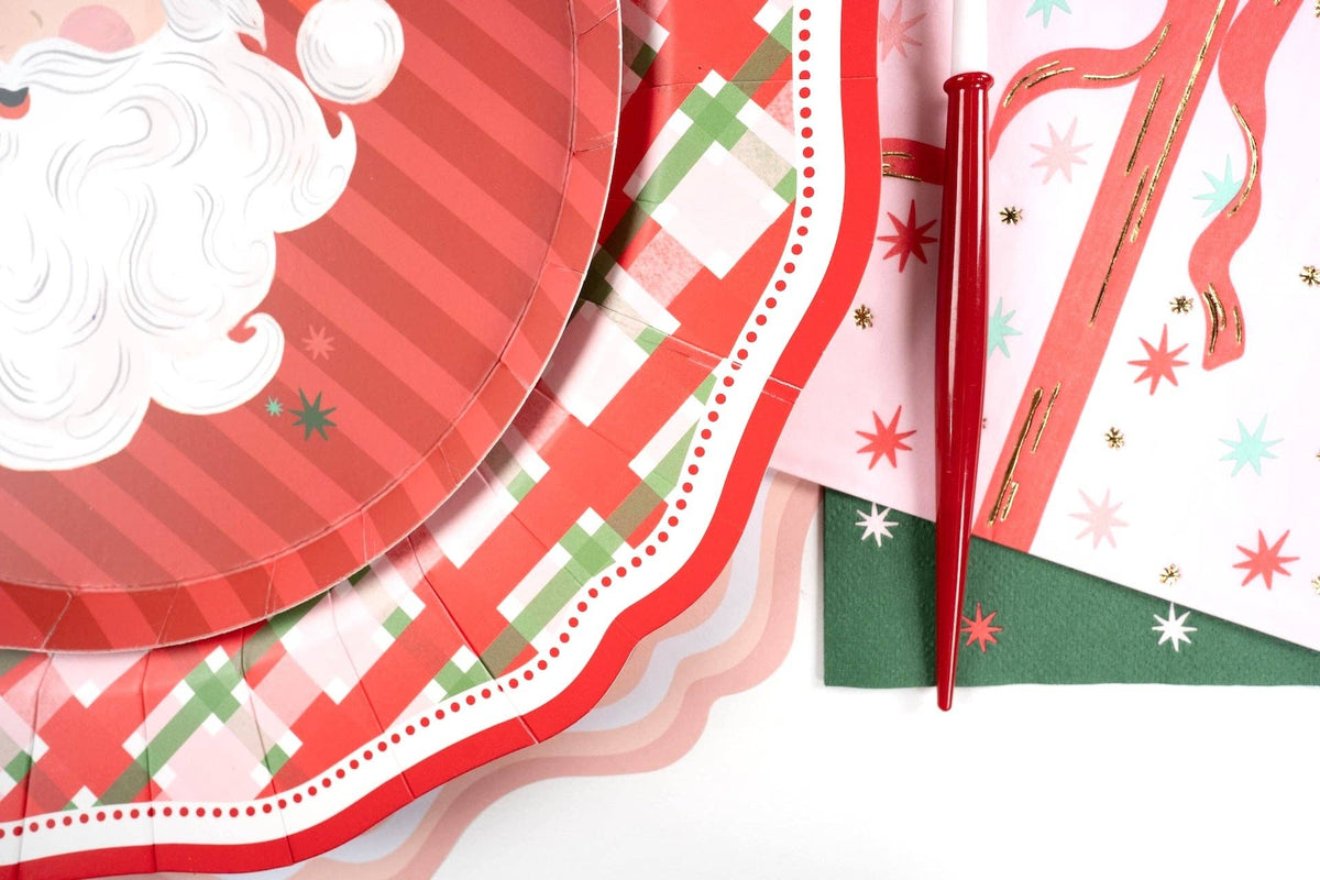 Close-up of a vintage Santa plate layered on the plaid dinner plate with a red-dot scalloped edge and a red utensil.