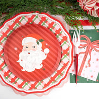 Place setting with a Santa plate, the green star guest towel, evergreen sprigs, and a red bow.