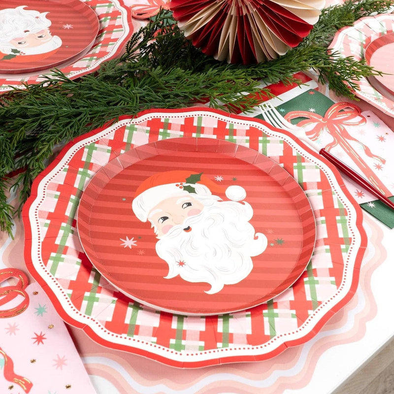 Place setting with the Santa dessert plate on a wreath dinner plate, a striped runner, evergreen, and a gold fork.