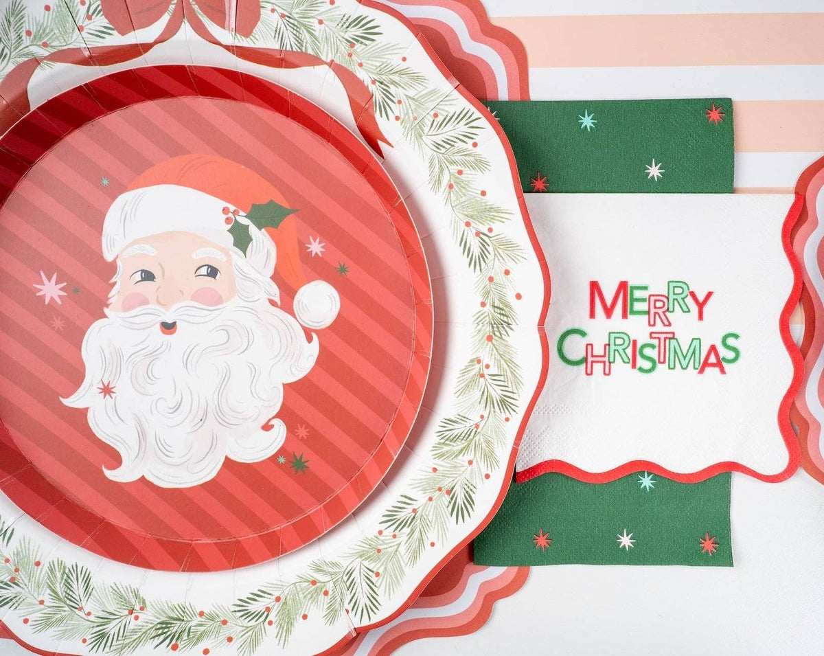 Place setting with the Santa dessert plate on a green wreath-rim plate, a Merry Christmas banner, and a gold fork.
