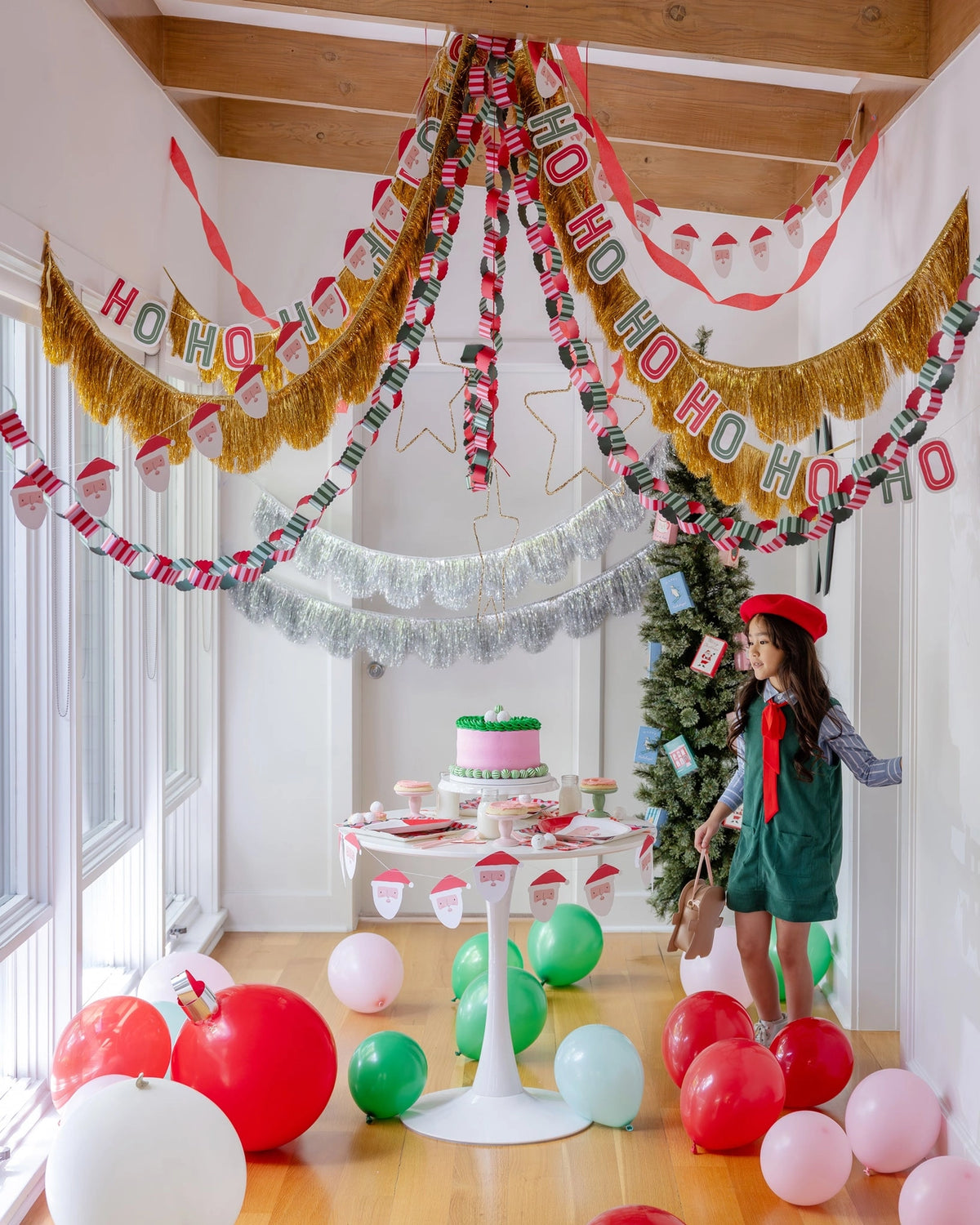 Christmas party room with garlands, balloons, an elf figure, and the Santa plates on a dessert table.