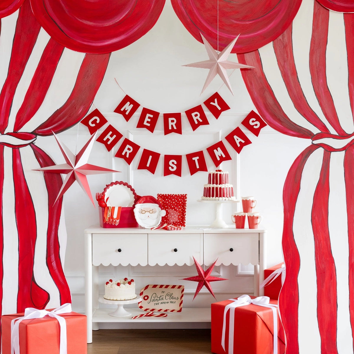 Styled room with the Santa plates on a console, a party banner, striped curtain, and wrapped gifts.