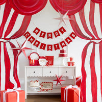 Styled room with the Santa plates on a console, a party banner, striped curtain, and wrapped gifts.