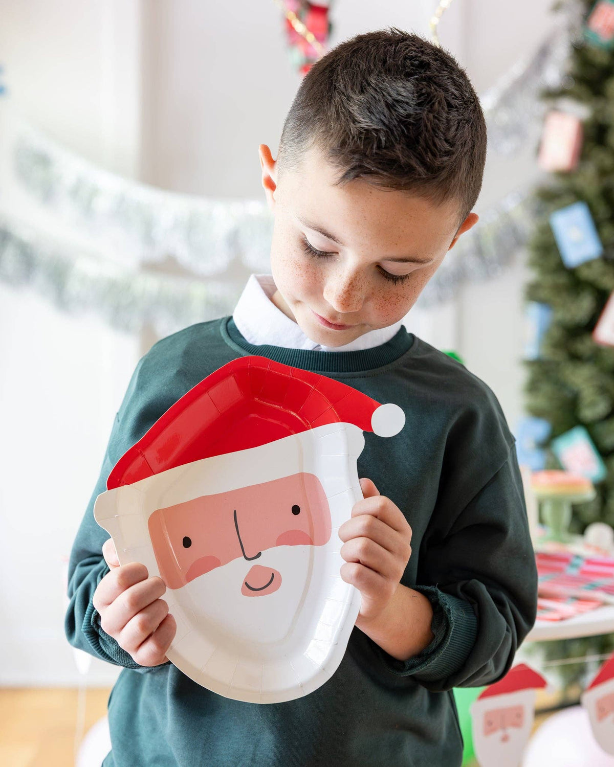 Child holding up a Santa-shaped paper plate at a holiday setting