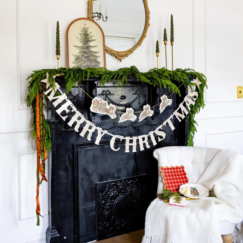 Mantel with greenery and vintage Christmas banner of Santa and reindeer.