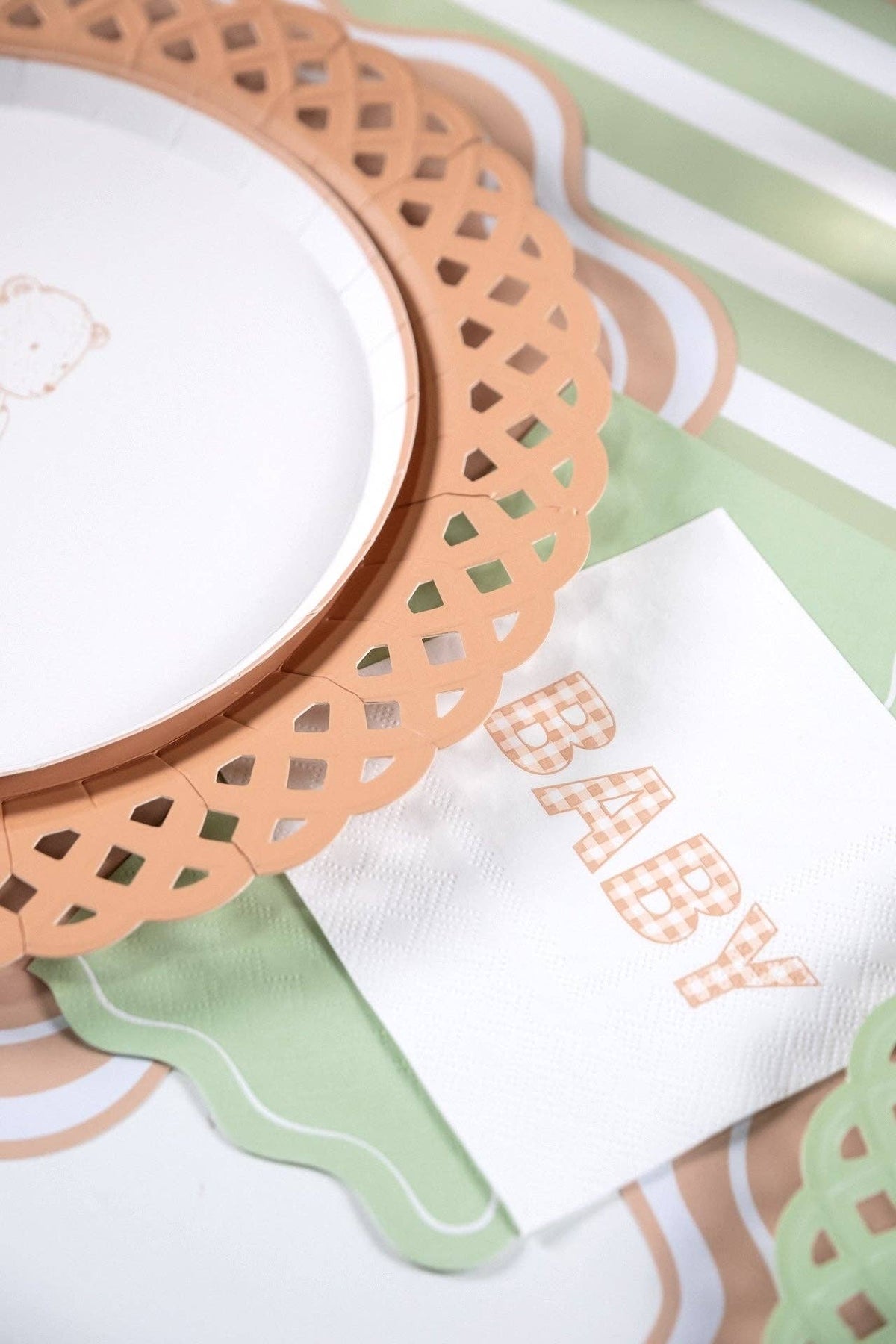 Close up angled view of the scalloped basketweave paper plate acting as a charger underneath a white dinner plate.