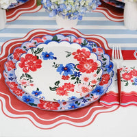 Scalloped Paper Dinner Plates stacked with a floral dessert plate on a red wavy-edge placemat.