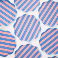Multiple pink and blue cabana stripe scalloped paper plates arranged in a repeating pattern on a white background.