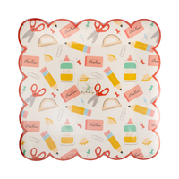 Front of school supplies scalloped paper plate with red scalloped edge and cream background printed with pencils, pink erasers, scissors, glue bottles, protractors, paper clips, and pencil shavings