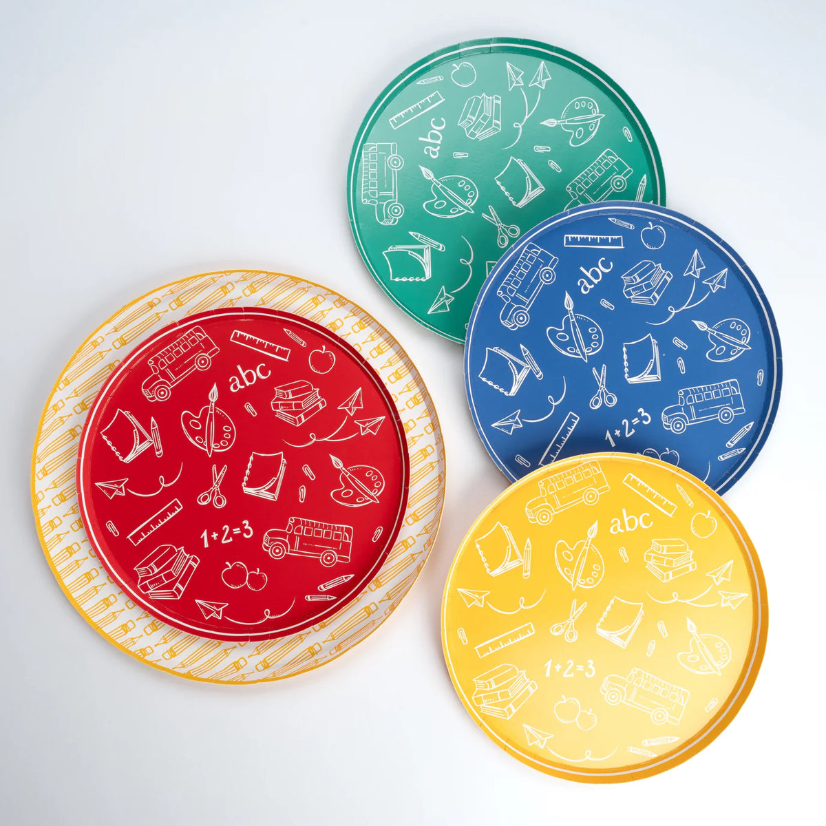Four primary‑color school icon plates fanned around a yellow pencil dinner plate on white backdrop.