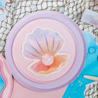 Seashell napkin layered on stacked pink and lilac mermaid plates