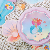 Seashell napkin beside a mermaid plate on a fishing-net backdrop