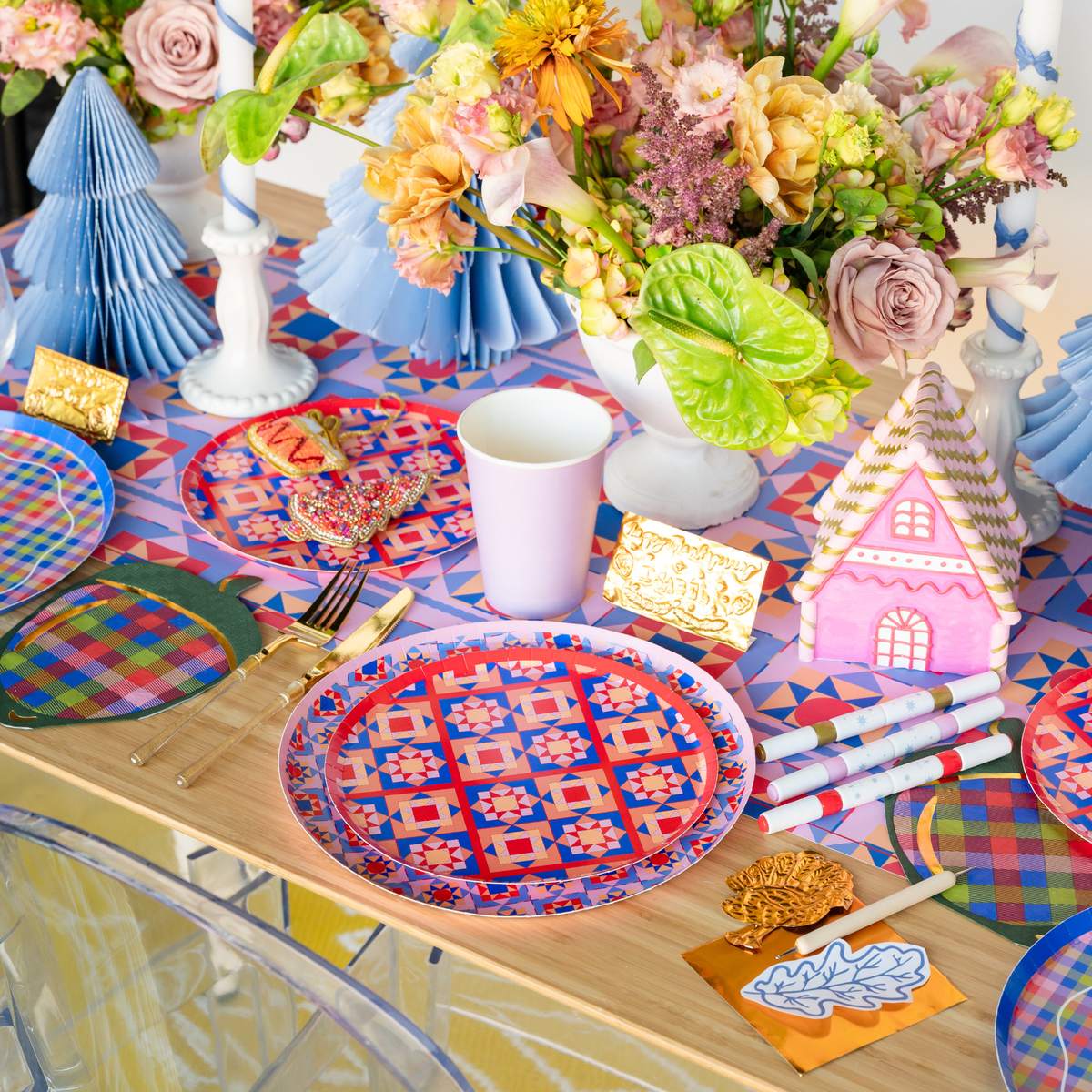 Styled Season of Cheer fall tablescape showing the purple turkey napkins with geometric plates, paper fans, a gingerbread house, and vibrant autumn décor.
