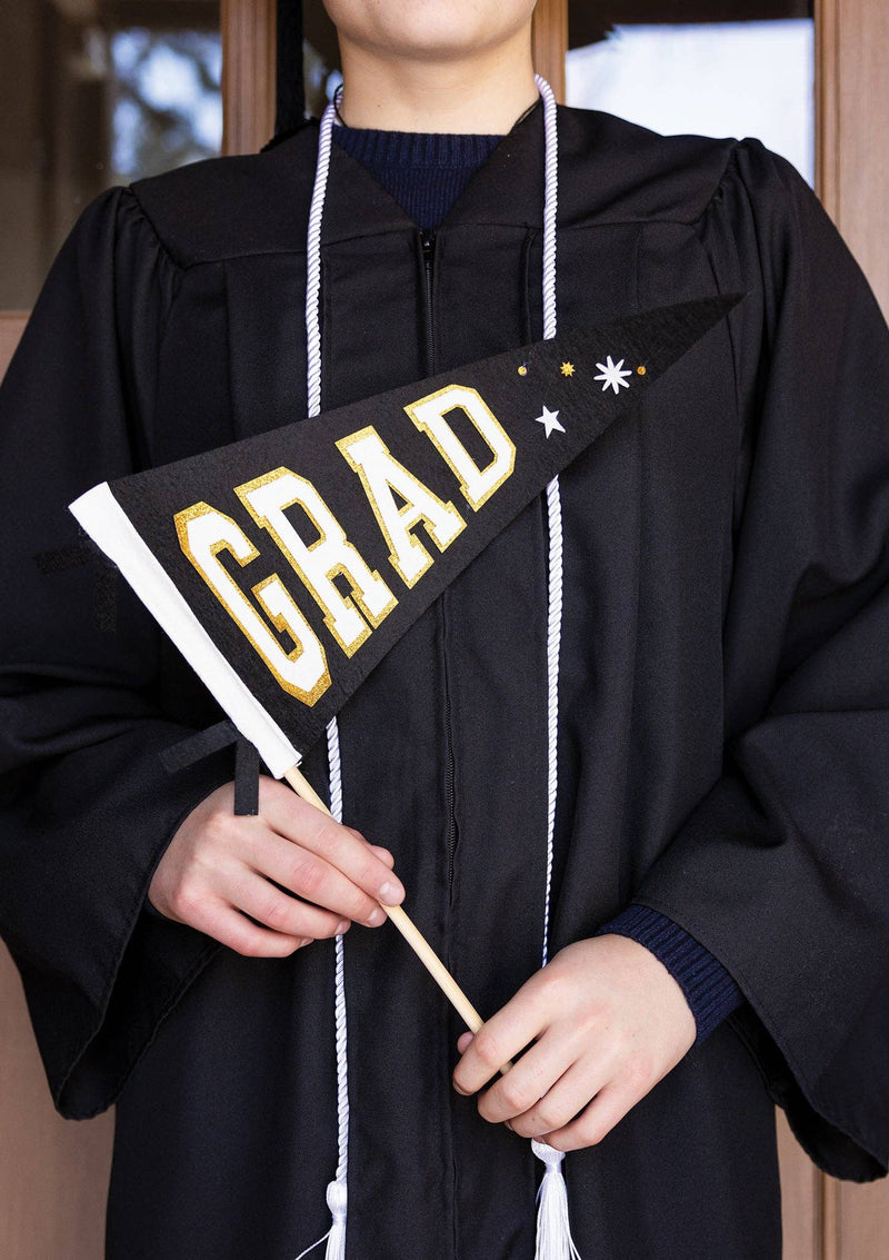 A graduate holding a black and gold felt graduation pennant as a matte, no-glare photo prop.