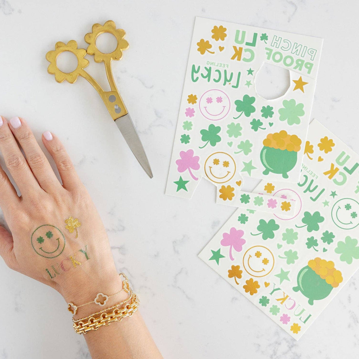 Hand wearing shamrock temporary tattoos next to tattoo sheets