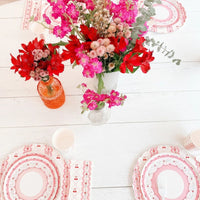 Overhead view of a party table with cherry place settings and bright pink flowers