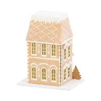 Side view of the lighted Christmas house showing the tall chimney and the detailed gingerbread-style roofing.