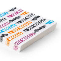 Side view of the stacked race car napkins showing the thickness and the multicolor foil print along the edges.
