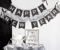 Silver fringe backdrop with a Happy New Year banner above a party table