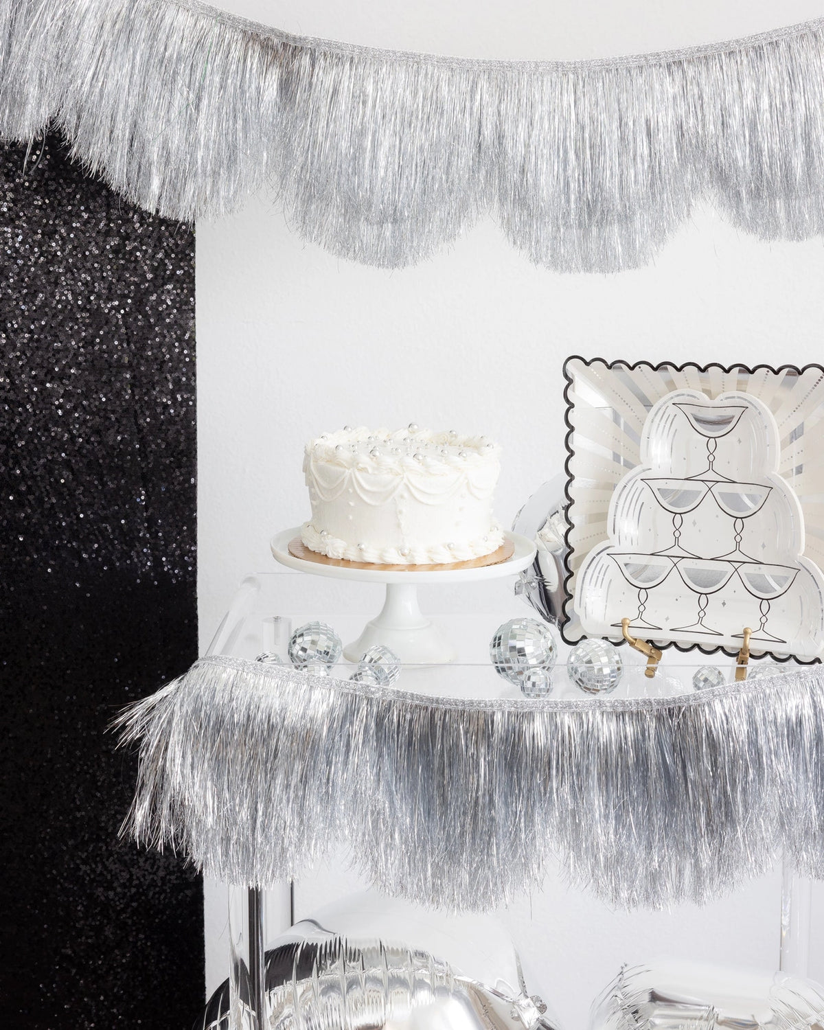 Silver starburst square plates styled on a cake table with silver fringe display