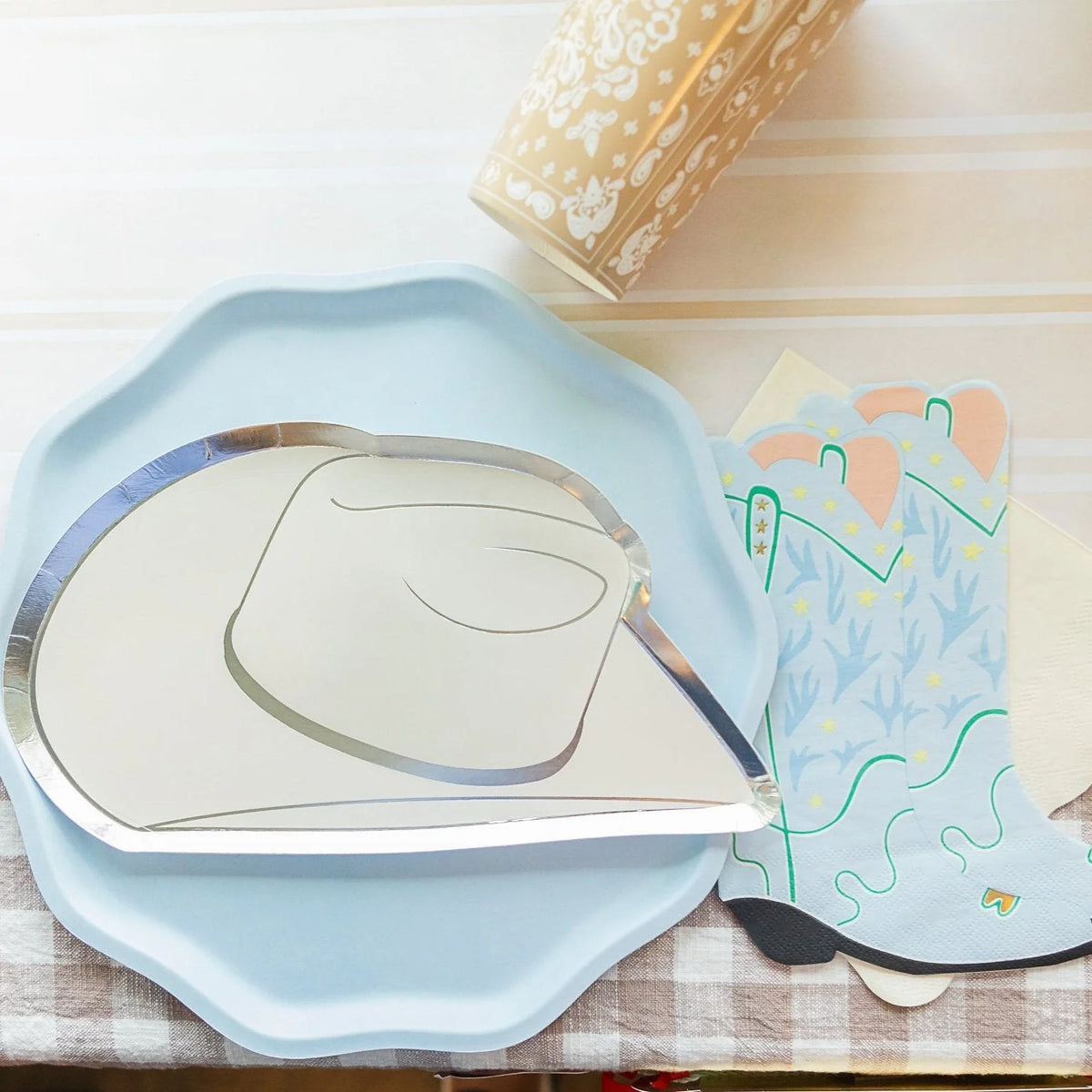 Sky blue compostable plate styled with silver cowboy hat plate and boot napkins.