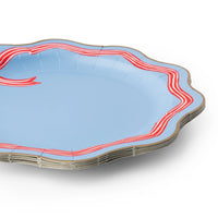 Stack of sky blue paper dinner plates with a red-and-white striped bow motif, striped ribbon border, and wavy gold edge.