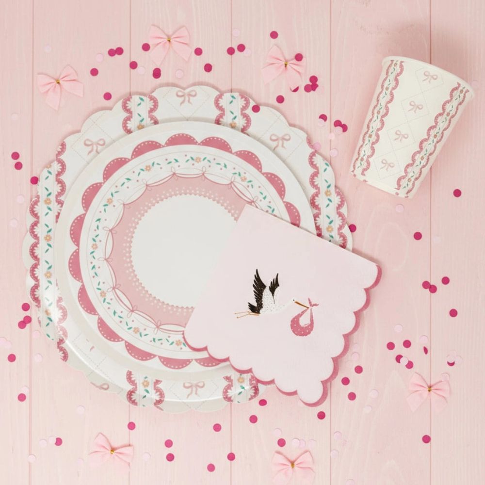 Stork napkin layered over a pink scalloped plate with heart confetti