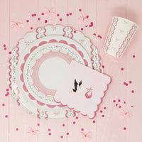 Stork napkin layered over a pink scalloped plate with heart confetti