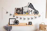 Decorative shelf with Halloween-themed items including Spooky things ahead paper plates, books, plates, and a banner on a white wall.