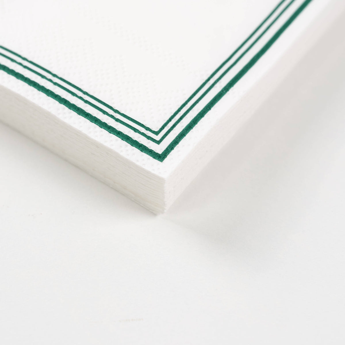 Close-up stack of golf cocktail napkins showing green border detail