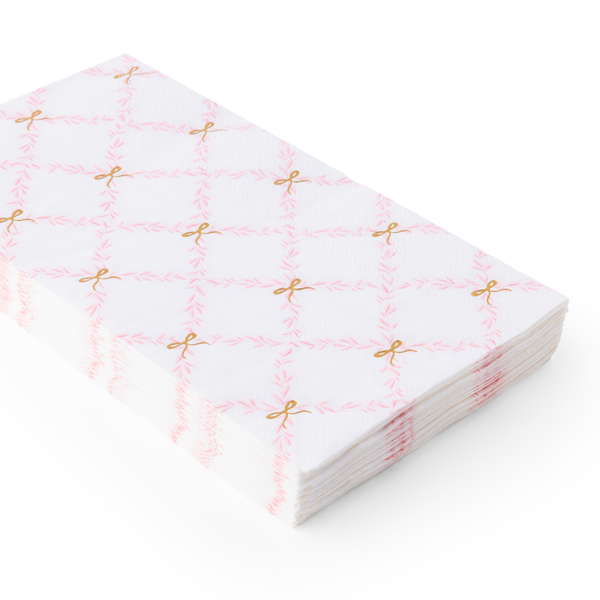 Stacked paper guest towels featuring a pink trellis pattern with gold bow details.