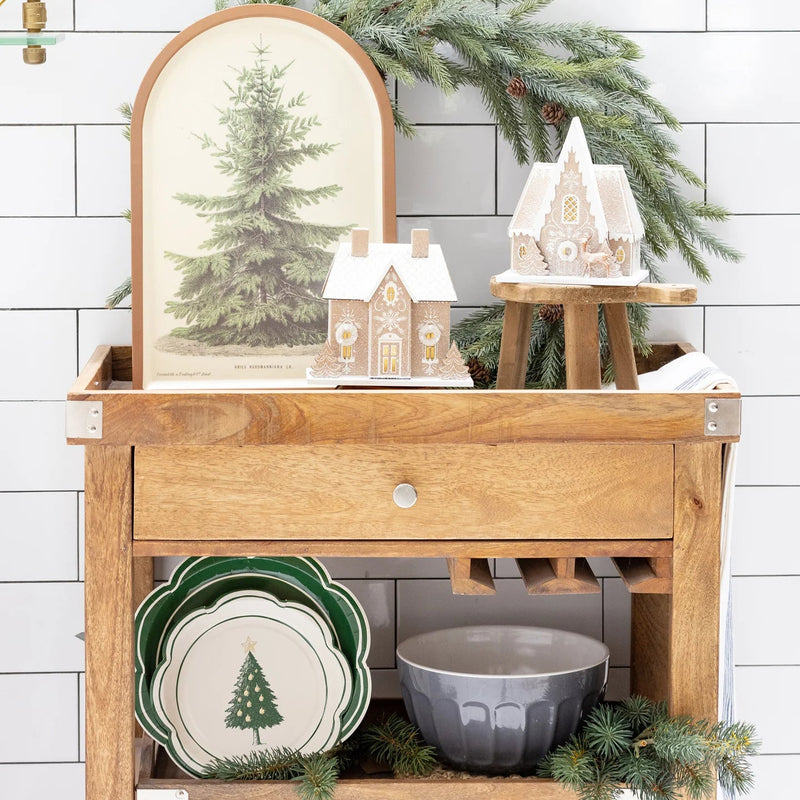 Close-up of the stacked Evergreen tree plates layered with a solid green charger, displayed on a wooden cart as holiday decor.