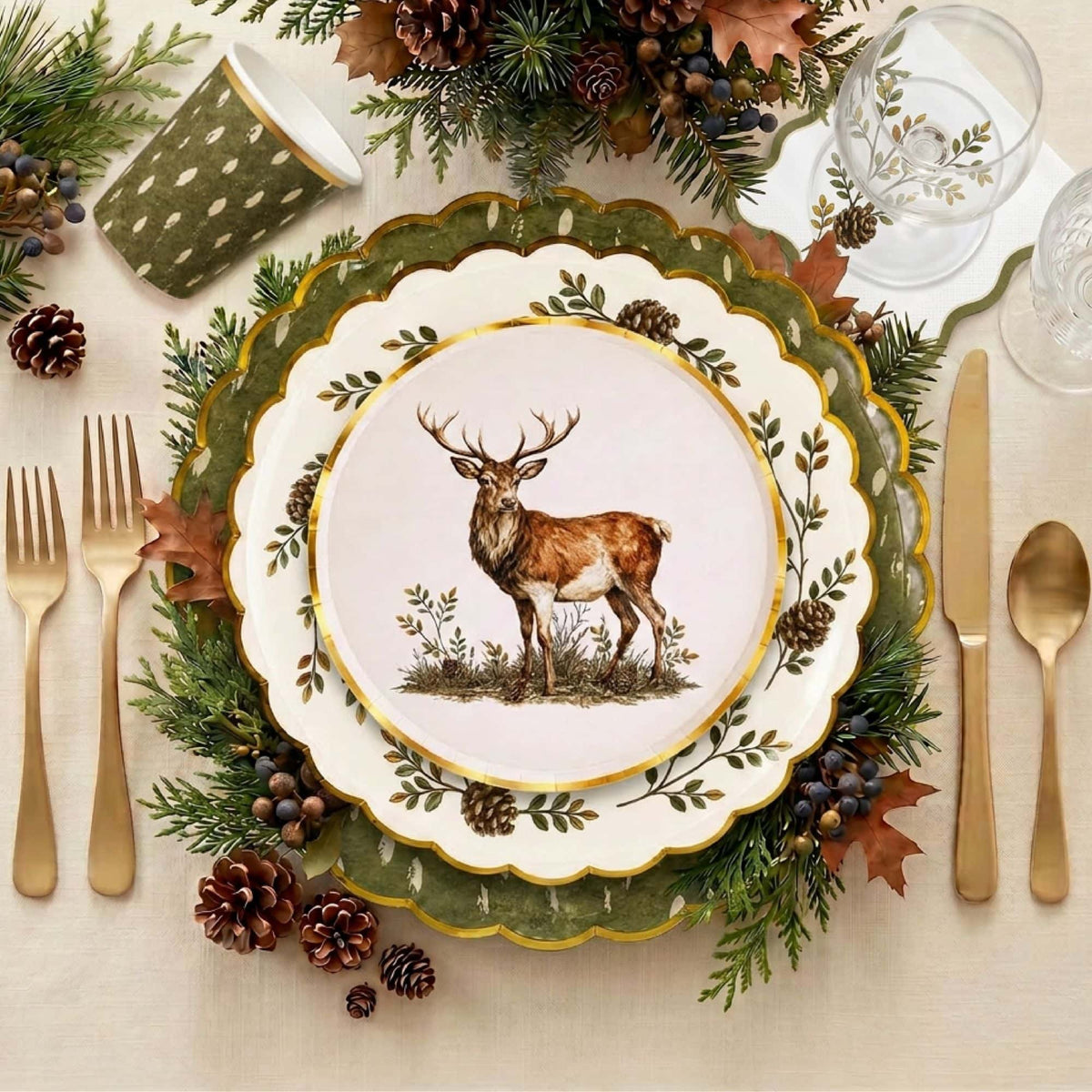 Woodland place setting with the stag plate on a pinecone plate and olive charger, gold cutlery, pinecones, and evergreen.