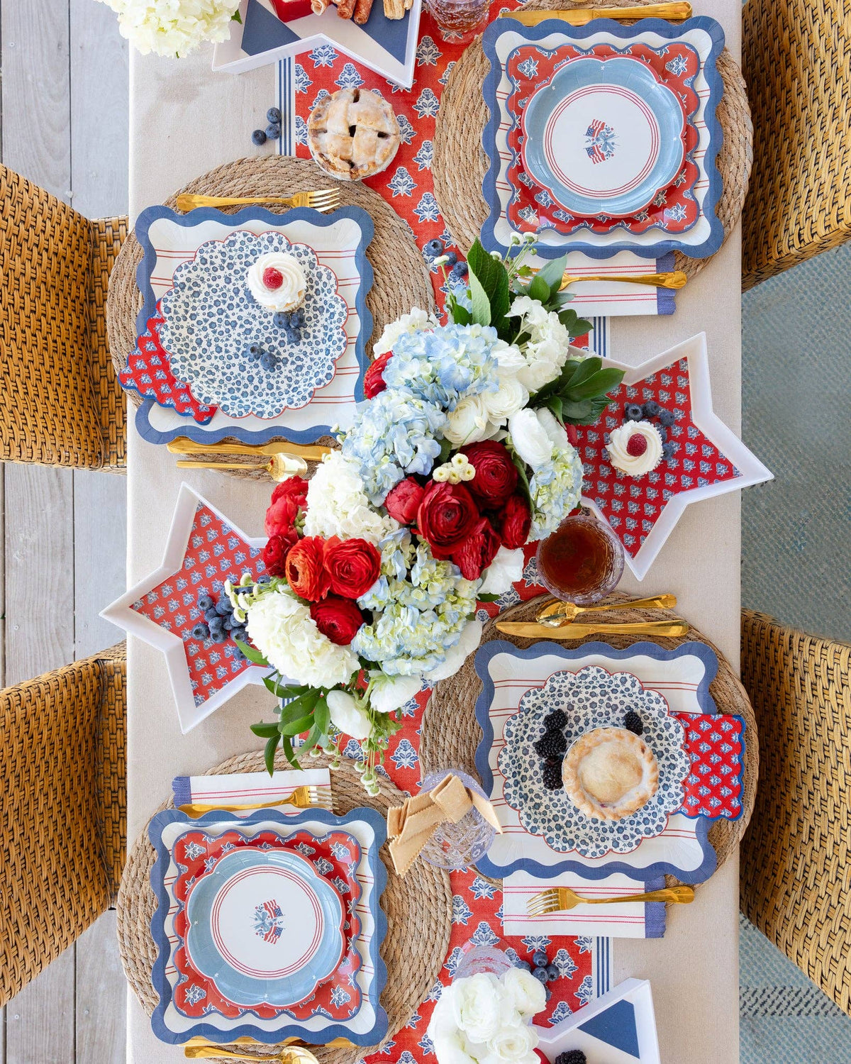 Overhead view of 4th of July tablescape with star shaped bamboo trays, scalloped paper plates, and hydrangea centerpiece