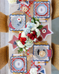 Overhead view of 4th of July tablescape with star shaped bamboo trays, scalloped paper plates, and hydrangea centerpiece