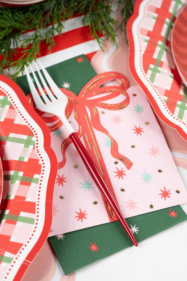 Place setting with the green star guest towel folded beside a red lace doily charger, a gold fork, and a striped runner.