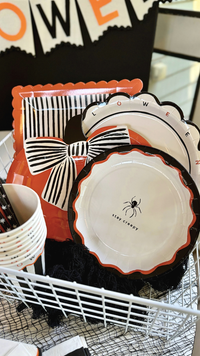 Scalloped white Halloween paper plates with a black edge and black and orange letters spelling Halloween around the rim