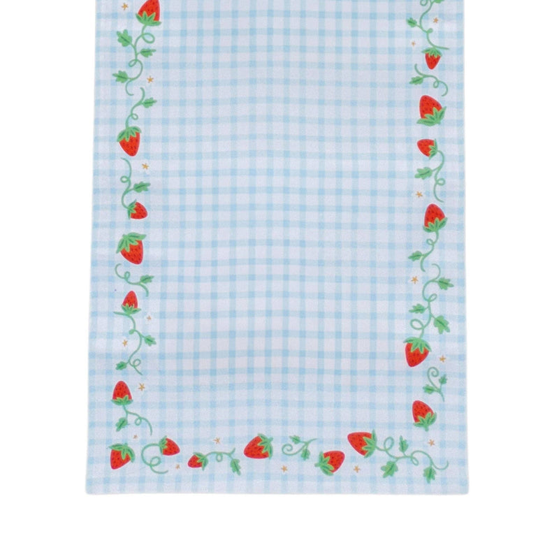 Close-up corner of the strawberry gingham table runner showing red berries, curling green vines, and tiny gold stars along the blue gingham edge.