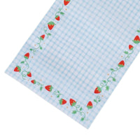 Angled corner of the blue gingham strawberry table runner showing the berry-and-vine border and gingham check.