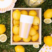 Striped party cups stacked inside wooden crate with fresh lemons