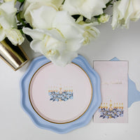 Flat lay of a party spread featuring menorah plates, blue plates, gold cups, and blue confetti.