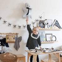 Ghost mylar balloon and ghost garland styled in a kids Halloween playroom with a set table and cupcakes