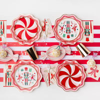 Flat lay of a party table featuring the candy cane swirl plates layered with Nutcracker plates and gold cups.