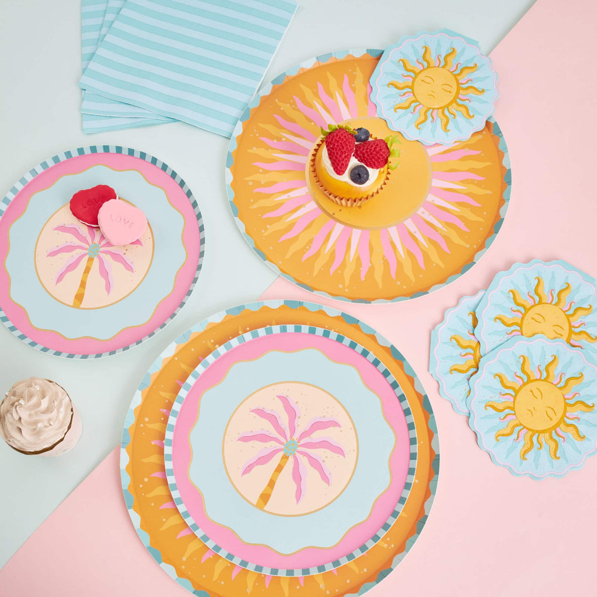 Sun shaped cocktail napkins styled in a summer party flatlay with sunburst plates, palm-print plates, and striped napkins.