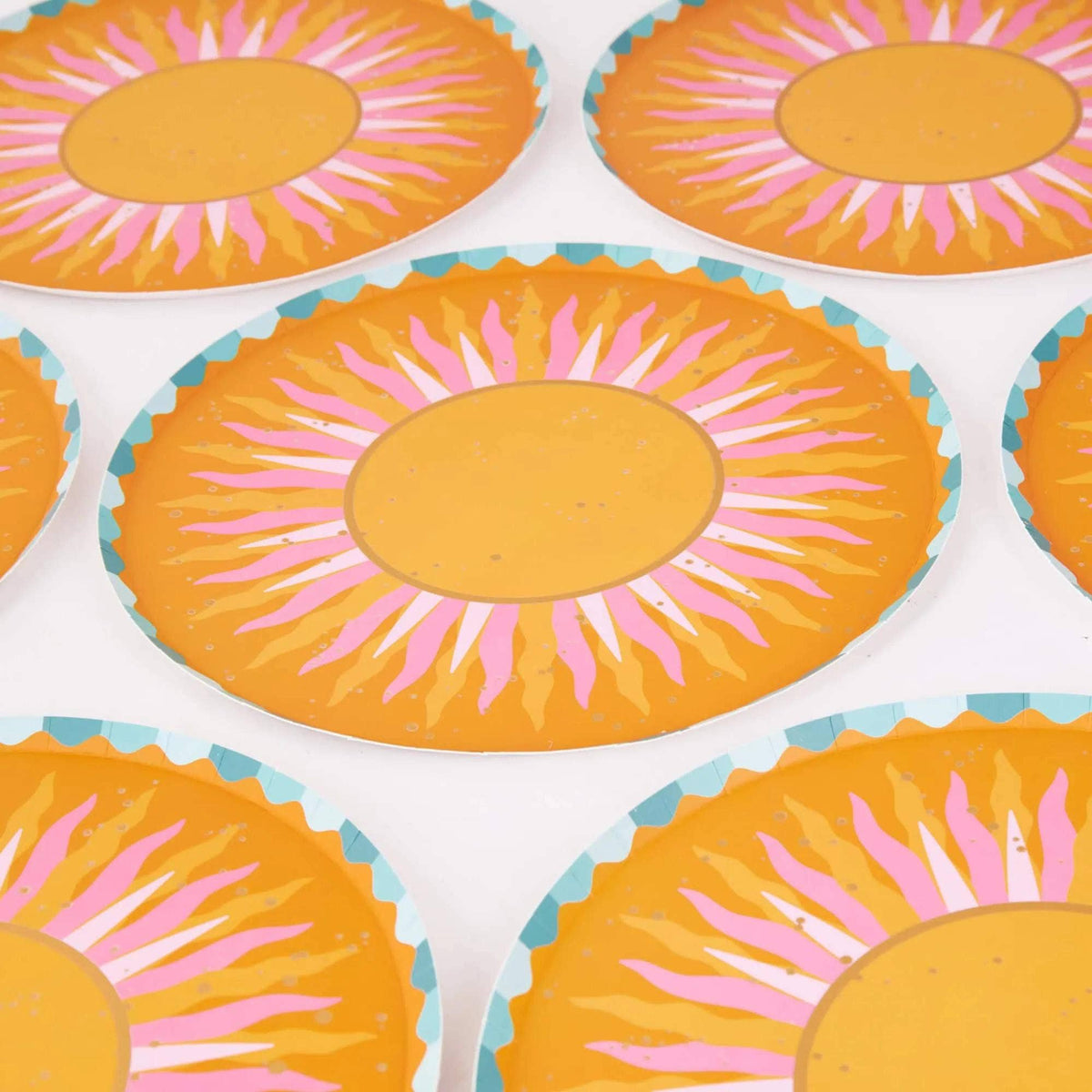 Repeating pattern of sunburst dinner plates with golden centers and pink-and-orange rays.