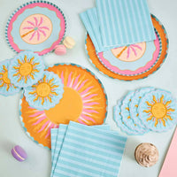 Sun collection spread with a large sunburst plate, sun-shaped napkins, a palm plate, and blue striped napkins.