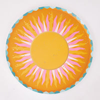 Single orange sunburst paper dinner plate with a golden center, pink rays, gold flecks, and a teal scalloped rim.